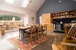 a dining room with a table and a kitchen at Papple Steading in East Linton