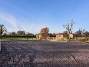 a barn with a fence and a field with houses at Elm Lodge in Ashbourne