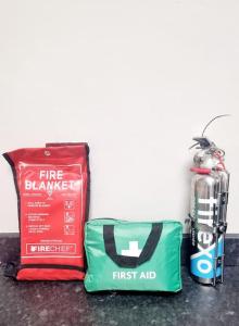 a bag and a first aid bag next to a fire extinguisher at Stylish Apartment, self check-in, 25mins to Gatwick Airport in Thornton Heath