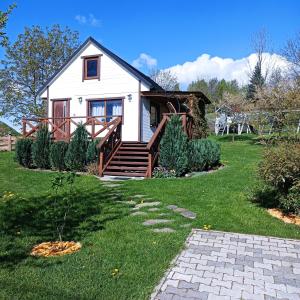 a small white house with a porch and a yard at Drewniany Domek in Bukowiec