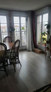 a dining room with a table and chairs and windows at Appartement loft. A 2km de la colline d'Elancourt in Trappes