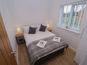 a bedroom with a bed with two towels on it at Rowan Lodge in Ashbourne