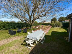 a picnic table and chairs in a yard with a tree at Maison de vacances in Olonne-sur-Mer