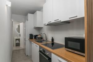 a kitchen with white cabinets and a black microwave at CASA ANNA BOUTIQUE SUITE Apartment New in Adamas
