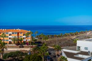 an orange building with the ocean in the background at Green House - Modern Villa in Tenerife, Spain in Guía de Isora