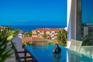 a blue table on a balcony with a view of the ocean at Green House - Modern Villa in Tenerife, Spain in Guía de Isora