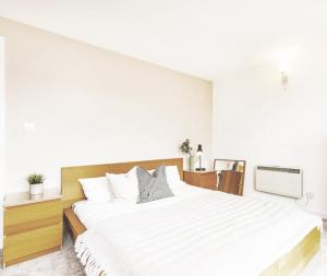 a white bedroom with a large bed and a tv at City Centre Rooms in Cardiff