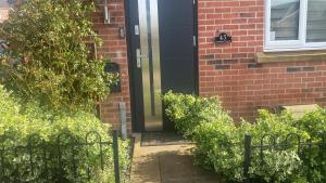 a black door on a brick house with bushes at C.K. APARTMENT in Foleshill