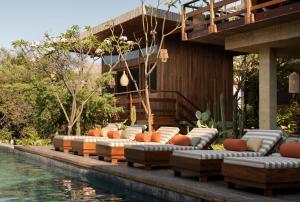 a patio with couches next to a swimming pool at Ennea Hotel - Adults Only in Puerto Escondido