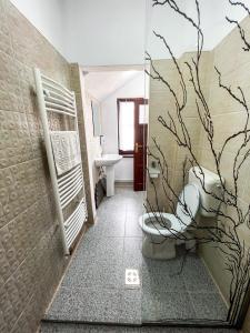 a bathroom with a toilet with a branch mural on the wall at Casa Forrás in Borsec