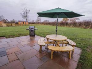 a picnic table and bench with an umbrella and a grill at Ash Lodge in Ashbourne