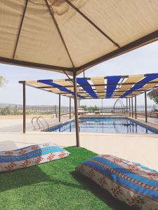 a swimming pool with two beds under a large umbrella at شاليه للايجار اليومي والاسبوعي in Amman