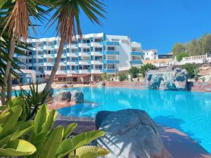 a large swimming pool with a resort in the background at Sissy Tenerife Apartman in San Miguel de Abona