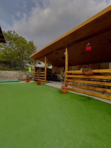 a pavilion with green grass in front of a building at Cabanutele La Denisa in Dubova