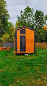 een klein huisje in een grasveld bij Przytulny domek 150 m od jeziora in Charzykowy