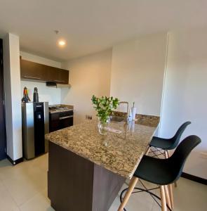 a kitchen with a granite counter top and two chairs at Suite Estelar - A Pasos del Aeropuerto in Rionegro