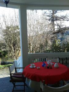 uma mesa com uma toalha de mesa vermelha no alpendre em Swanlake Villa em Meina