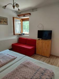 ザラカロシュにあるLonci apartmanの赤いソファとテレビ付きのベッドルーム