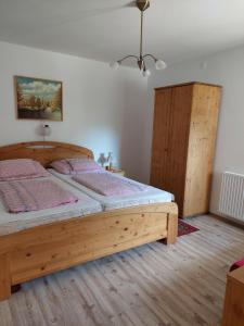 ザラカロシュにあるLonci apartmanのベッドルーム1室(木製ベッド1台、木製キャビネット付)