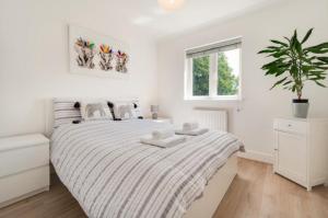 een witte slaapkamer met een bed en een potplant bij 3 Bed Holiday Home in Llandeilo with log burner in Llandeilo