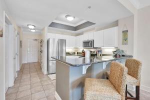 a kitchen with a counter with two chairs and a refrigerator at Crystal Tower 206 Amenities galore in Gulf Shores