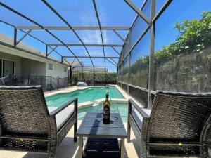 a bottle of wine sitting on a table near a swimming pool at Luxury 4bd Villa at Windsor Palms Resort. in Kissimmee