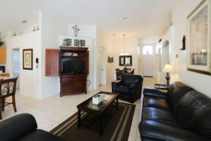 sala de estar con sofá de cuero y TV en Luxury 4bd Villa at Windsor Palms Resort. en Kissimmee