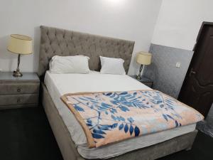 een bed in een slaapkamer met 2 nachtkastjes en 2 lampen bij Syedah 's Homestay in Lahore