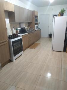 a kitchen with a white refrigerator and wooden cabinets at Pousada 4 estações in Machadinho