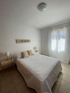 um quarto branco com uma cama e uma janela em Las Margaritas Binibeca Menorca em Binibeca