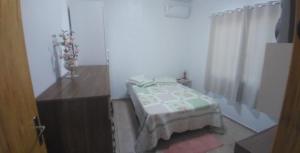 a bedroom with a bed and a dresser with a vase of flowers at Pousada 4 estações in Machadinho