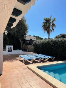 uma piscina com espreguiçadeiras e uma palmeira em Las Margaritas Binibeca Menorca em Binibeca