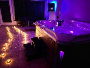- une salle de bains pourpre avec une baignoire éclairée au sol dans l'établissement Les bulles d'or, à Flémalle-Grande