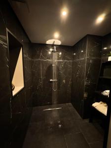 a bathroom with a black tiled wall with a shower at Les bulles d'or in Flémalle-Grande