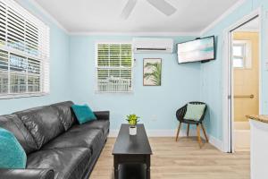 a living room with a black leather couch at Parrot Beach Cottages Suite #2 in Siesta Key