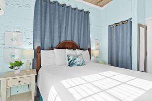 a bedroom with a large bed with blue curtains at Parrot Beach Cottages Suite #2 in Siesta Key +12 photos