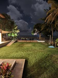 a backyard with a lawn with palm trees at Slater's House - Casa de praia em frente ao mar in Paripueira