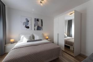 Habitación blanca con cama y espejo en Apartment Tinel, en Trogir
