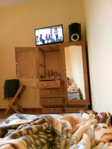 a bedroom with a dresser and a tv in a mirror at Casa de campo vidal in Cochabamba