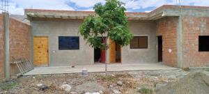 ein Backsteinhaus mit einem Baum davor in der Unterkunft Casa de campo vidal in Cochabamba