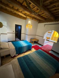 1 Schlafzimmer mit 2 Betten, einem Tisch und einem Spiegel in der Unterkunft Maison La Vallée Des Figues Dadès in Tamellalt