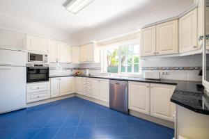 uma cozinha com armários brancos e piso em azulejo azul em Vicente Mar Luxury Villa - Free WiFi em Albufeira