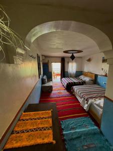 Pokój z kilkoma łóżkami w pokoju ze ścianą w obiekcie Maison La Vallée Des Figues Dadès w mieście Tamellalt