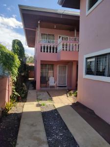 een roze huis met een balkon en een patio bij Departamento Ángeles del Arenal #2 in Fortuna