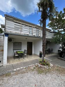 ein Haus mit einem Tisch, Stühlen und einer Palme in der Unterkunft Apartment Irena in Jadranovo