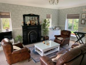 sala de estar con muebles de cuero y chimenea en Dungimmon House en Ballyconnell