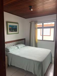 a bedroom with a large bed with a window at Residencial Marémansa pousada apto 01 in Governador Celso Ramos