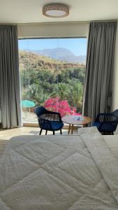 a bedroom with a bed and a table and a large window at WADI BANI KALED REST HOUSE in Dawwah
