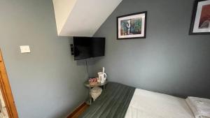 a bedroom with a bed and a flat screen tv at Bryn Bettws Lodge in Port Talbot