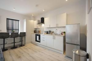 a kitchen with white cabinets and a stainless steel refrigerator at Modern 2 Bed Apt - 7ft Pool Table, Sheffield City Centre, FREE Parking, Netflix in Sheffield